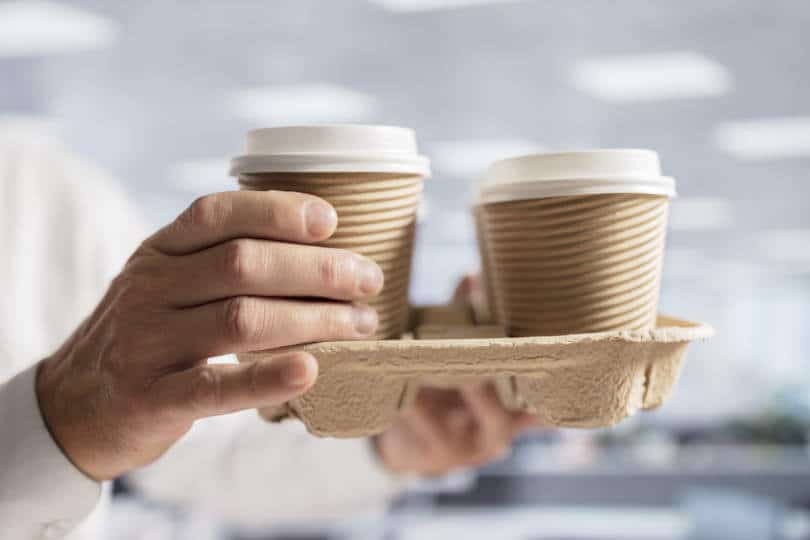 Man carrying coffee take out disposable cups on a coffee pod holder