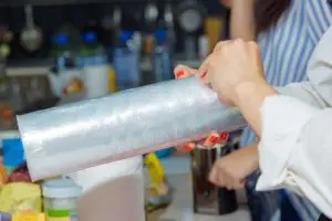 Woman holding a plastic wrap. Cooking in the kitchen
