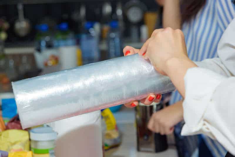 Woman holding a plastic wrap. Cooking in the kitchen