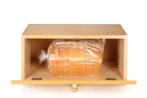 A breadbox with a fresh loaf of bread on a white background.