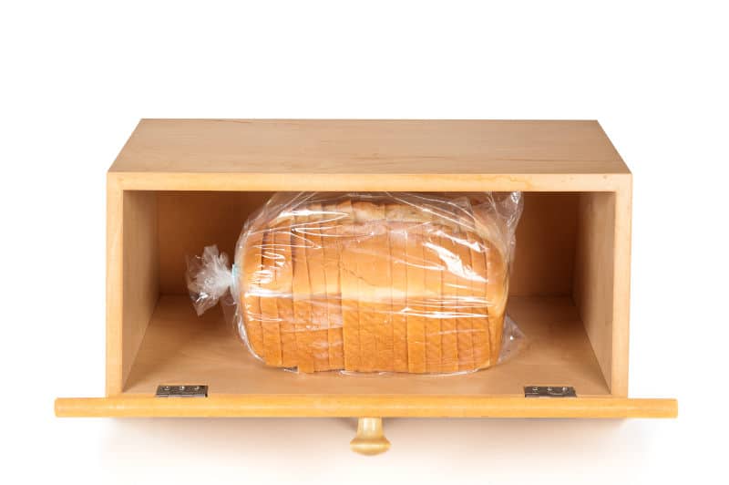 A breadbox with a fresh loaf of bread on a white background.