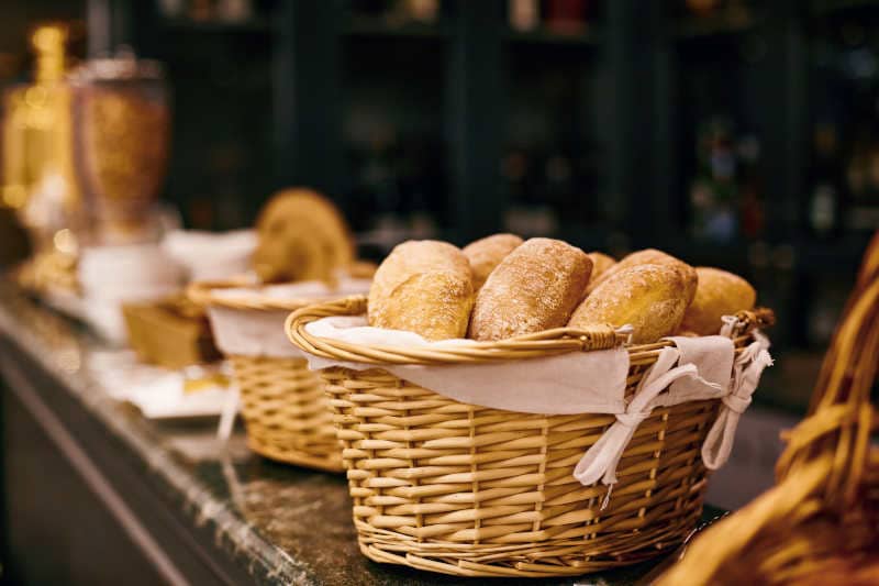 A bread proofing basket with fresh bread is on the table