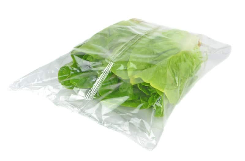 A sealed plastic bag of lettuce on a white background