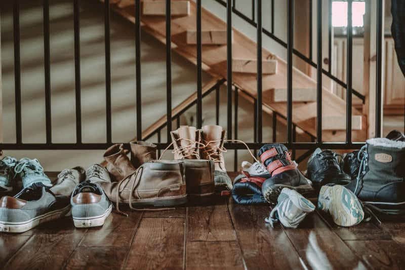 Shoes in a pile near some stairs in a college dorm