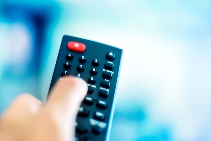 Man holding TV remote in hand and choosing tv canal