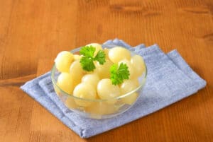 Bowl of small pickled onions with parsley on blue napkin