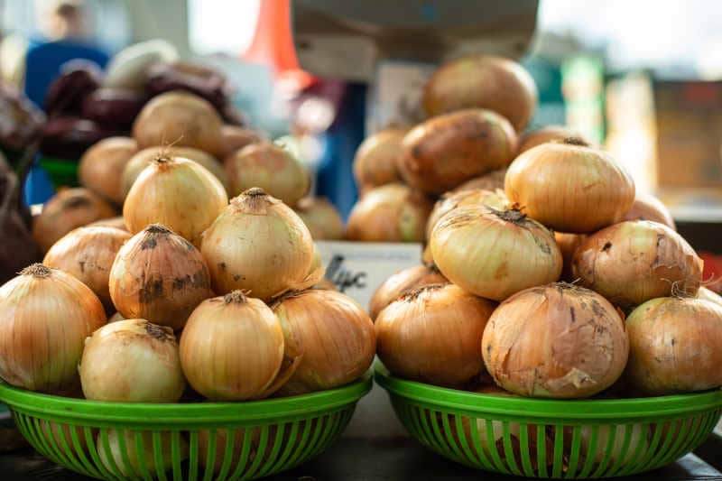 Two heaps of white onion bulbs in green plastic baskets