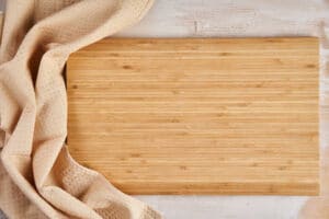 Flat lay shot of a bamboo chopping board with a towel by the side