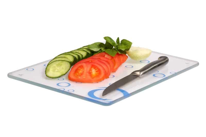 Cucumbers, onions, tomatoes on a glass cutting board