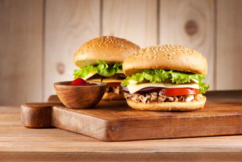 Hamburgers with meat turkey, cheese and vegetables on a rustic background