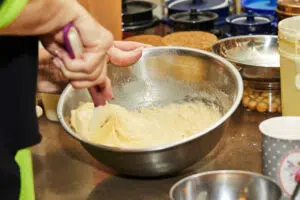 Women cooking at home, kneads dough for making pancakes.