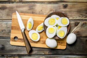 Sliced boiled eggs and knife on cutting board.