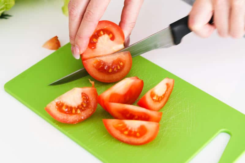 Cutting tomatoes on plastic cutting board