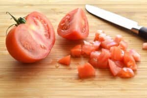 Sliced red tomato and knife on a bamboo cutting board