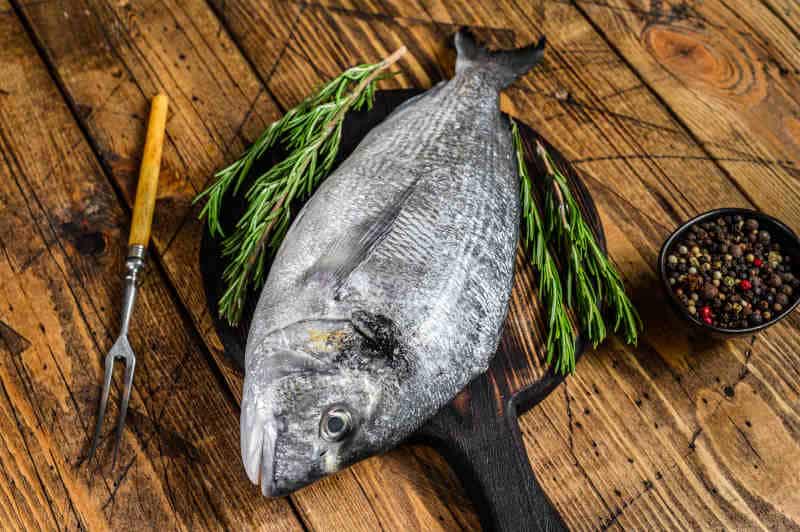 Raw sea fish with spices and herbs on a cutting board