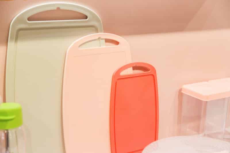 Various plastic cutting boards on the table. Kitchen utensils and accessories in trendy pastel colors.