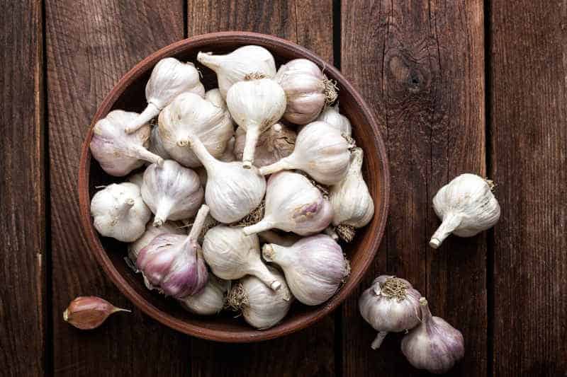 Fresh garlic in a basket on a wooden board