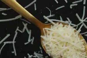 Shredded parmesan cheese on in a spoon on a black board