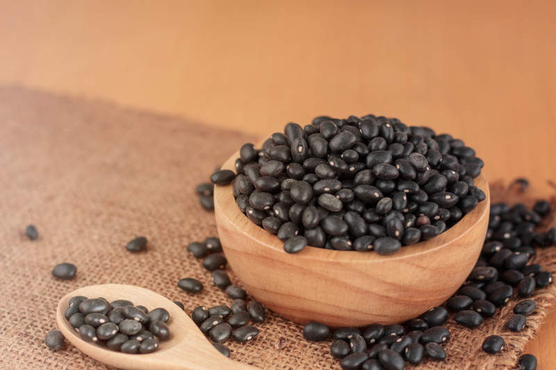 Black beans in bowls and spoon on wooden.