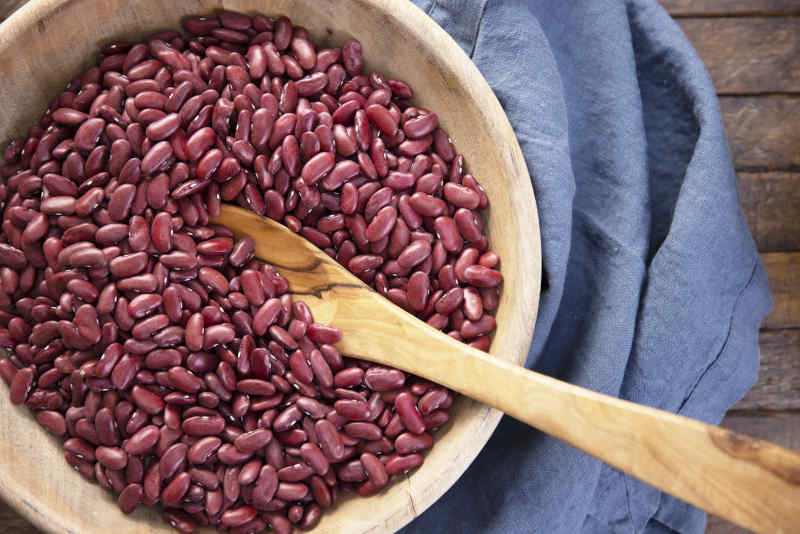 Dried Kidney beans in wooden bowl with spoon, flat lay.