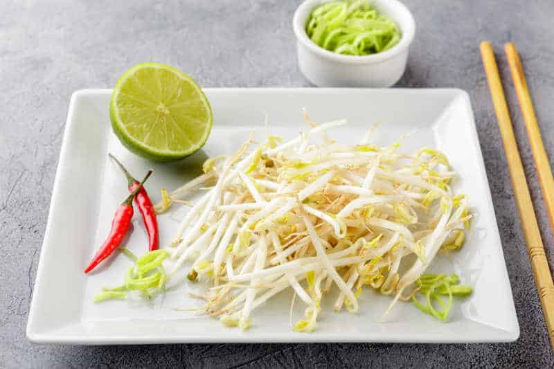 Fresh bean sprouts on white square plate and chopsticks. Concept of healthy foods, vegetarian food.