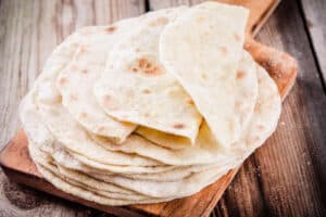 Stack of homemade wheat tortillas on wooden table