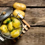Boiled potatoes with herbs on wooden table