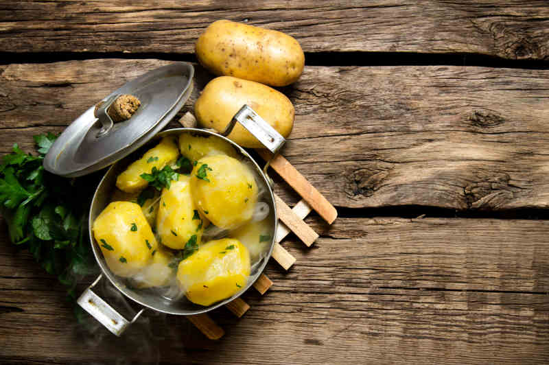 Boiled potatoes with herbs on wooden table