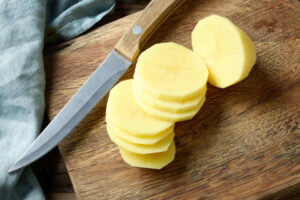 Fresh raw sliced potato on wooden cutting board