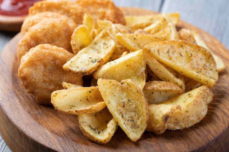 Tasty fried nuggets and potatoes on a table