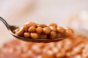 Closeup of a soup spoon full of baked navy beans