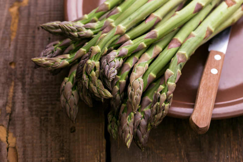 The fresh asparagus on the wooden background.