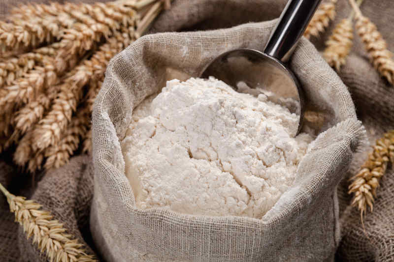 Flour in a bag on the table and spikelets.