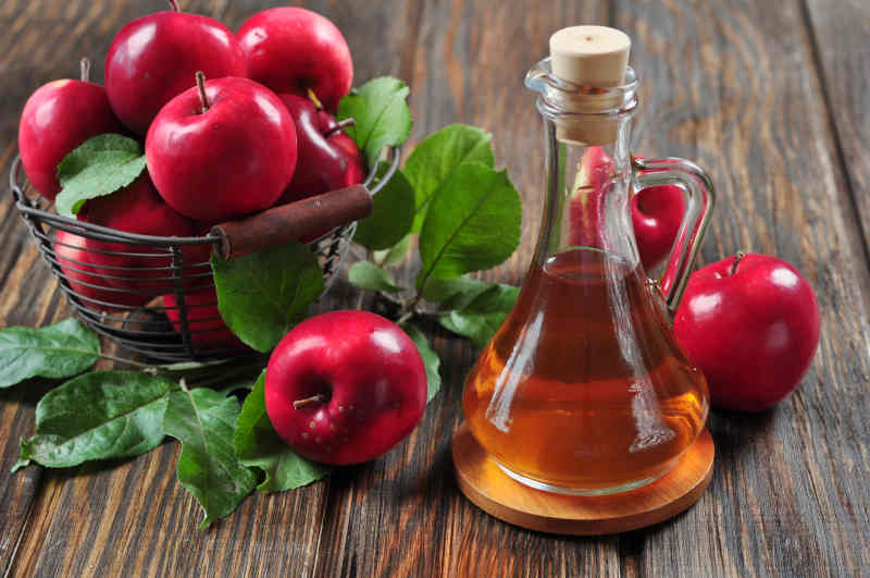 Apple cider vinegar in glass bottle and basket with fresh apples