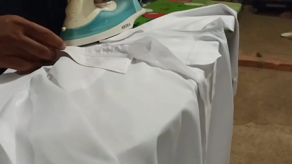 Ironing white Polyester shirt on ironing board